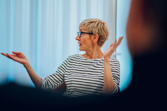 Senior woman psychologist on a group therapy session discussing mental health issues - Powered by Adobe