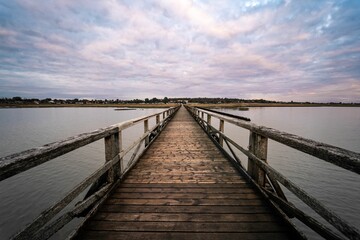 Fototapeta na wymiar Old wooden bridge over the river under a cloudy sky