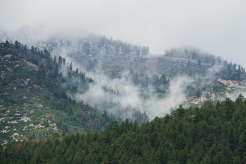 Aerial view of white fluffy clouds dancing in lush green mountains in Washoe Valley, Nevada