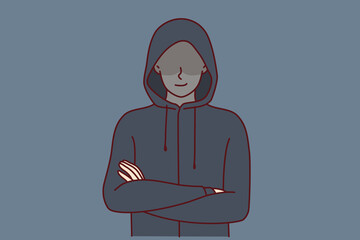 Anonymous man stands with arms crossed and hiding eyes behind hood for concept of secret surveillance or banditry. Anonymous guy hiding face wanting to remain incognito planning illegal activities 