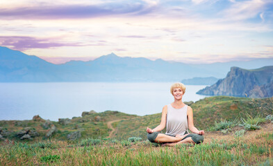 Senior woman doing yoga exercises with mountain sunset on the background