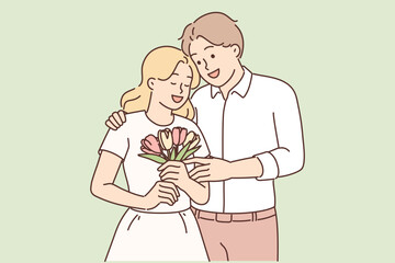Loving man hugging woman giving bouquet flowers in honor anniversary relationship or Valentine Day