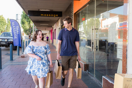 Young NDIS provider disability worker walking with girl with a disability shopping together