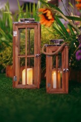 Vertical closeup of beautiful candles in wooden frames surrounded by flowers and plants