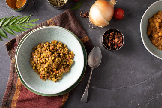 Bowl of Dahl Curry and ingredients around on dark background