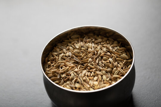 Spice tin of fennel seeds on dark background