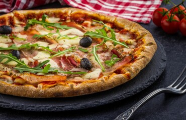 Closeup shot of a Pizza Tomate Jambon and some cherry tomatoes near
