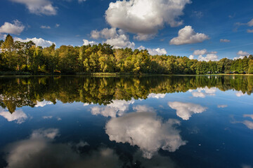 Naklejka na ściany i meble Natural landscape of the lake, high definition, the movement of waves against the background of the autumn forest. The reflection of clouds on the ripples of water. Germany.
