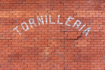 Brick wall background with Tornilleria text