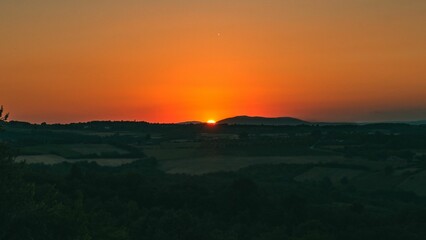 Beautiful landscape of orange sunset over the green fields.