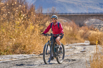 Obraz premium nice, active senior woman with her electric mountain bike on a trail tour in the dessert of Tabernas near Almeria, Andlusia, Spain