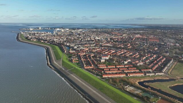 Aerial drone showcases Den Helder's coastal charm with stunning city views and serene ocean waves.