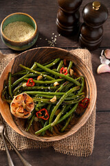 Roasted garlic green beans in wooden plate. Top view.