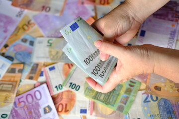 closeup female hands count paper 100 euro banknotes of european union, paper banknotes on table, concept of cash, payments, savings, banking, save up for vacation, car, winnings in a casino