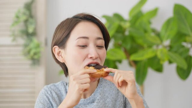 ドーナツを食べる若い女性　飲食イメージ	
