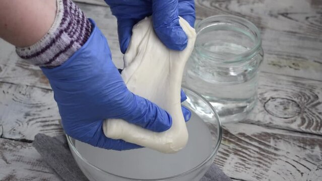 Making mozzarella cheese. Melting and carefully stretching spun paste taken from hot water. Preparing pasta filata types of cheese. Zoom out
