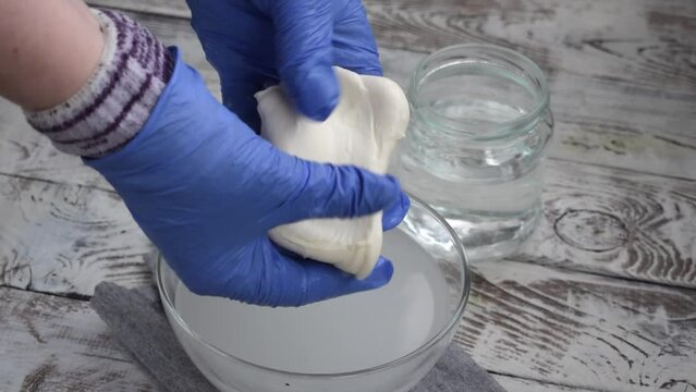 Making mozzarella cheese. Melting and carefully stretching spun paste taken from hot water. Preparing pasta filata types of cheese