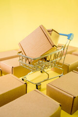 Shopping cart with boxes on a yellow background. The concept of sales, discounts, online shopping and delivery.