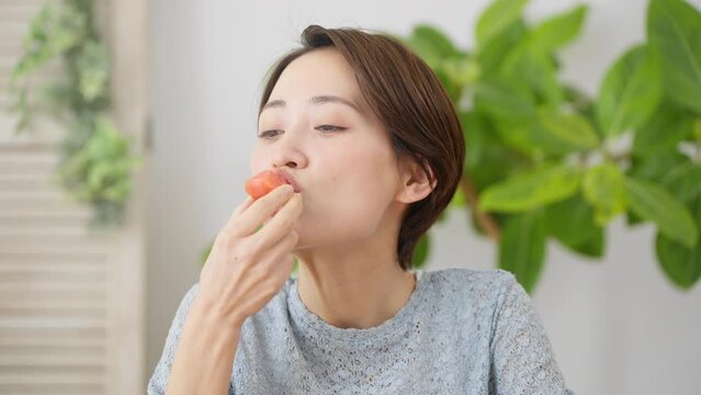 トマトを食べる若い女性　飲食イメージ	
