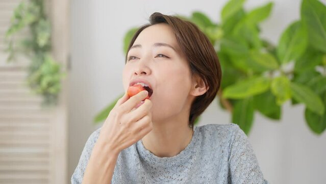 トマトを食べる若い女性　飲食イメージ	
