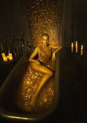 Portrait Closeup Beauty fantasy woman face in gold paint. Golden shiny skin. Glamorous fashion...