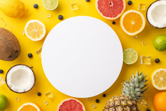 Stylish top view photo of coco nut ananas citrus fruits like orange, lemon, lime, and grapefruit on a bright yellow background and a blank circle for text is perfect for your summer marketing
