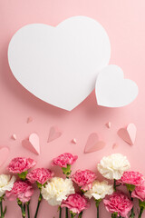 Mother's Day gift concept. Top vertical view flat lay of lovely carnation flowers, and pink paper hearts on a soft pastel pink background with two empty hearts for text