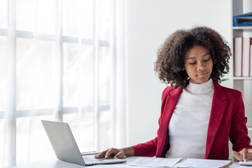 A young American woman is a start-up businesswoman, she sits in the office, managing and running a business from a young generation. Startup business management concept.