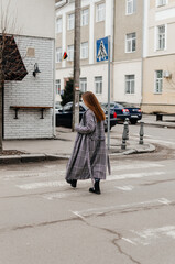 Fototapeta na wymiar a girl in a coat crosses the road