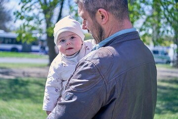 Closeup of a father holding his cute baby girl outdoors in Riga
