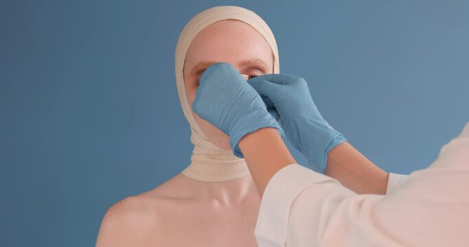 doctor putting on plastre on woman's nose who was in accident, close up portrait, domestic violence, victim of abuser, brain concussion , close up portrait isolated blue background