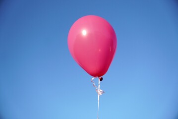 Single pink balloon against the blue sky in closeup