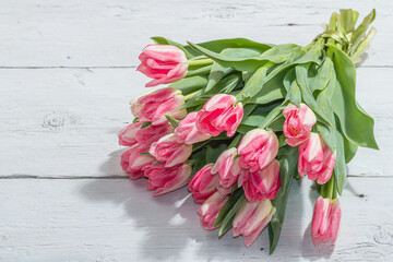 Bouquet of fresh pink tulips on white wooden background. Festive concept for Mother's Day