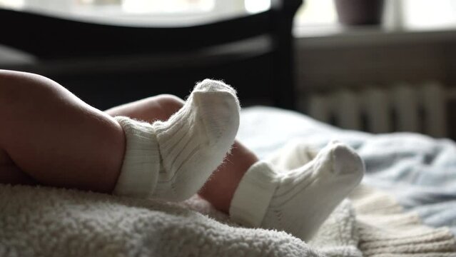 legs of a small child in white socks close-up. Slow motion. A newborn baby moves its legs. Reflex of early development. The concept of motherhood, family, birth. High quality 4k footage