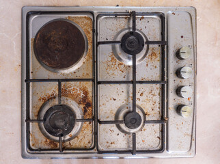 Dirty gas stove in the kitchen, top view. Gas stove with food remnants.