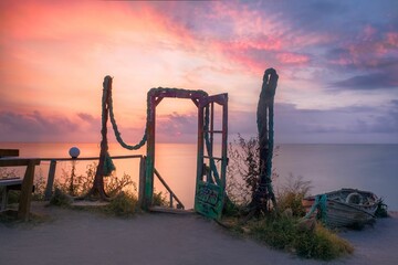Old metal door in background of sea during sunset in Vama Veche - obrazy, fototapety, plakaty
