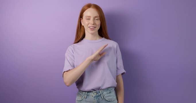 cheerful red-haired deaf girl wearing T-shirt and short says I am OK, and You conversation, communication, close up portrait isolated blue background. pointing with finger to camera