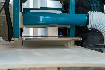 Craftsman works on a thicknessing machine in a workshop. 