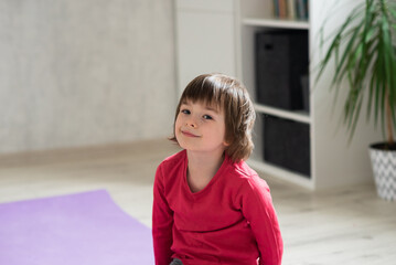 Happy girl in a red t-shirt looking at the camera at home in the room. The concept of peace and security at home