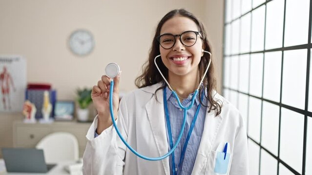 Young beautiful hispanic woman doctor smiling confident holding stethoscope at clinic