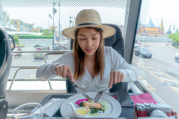 Asian traveller woman take a lunch on the restaurant bus between city tour by bus