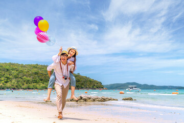 Asian couple travel Thailand beach todather, run and take a balloon