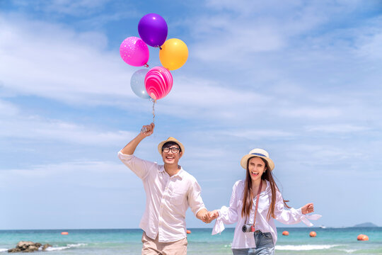 Asian couple travel Thailand beach todather, run and take a balloon