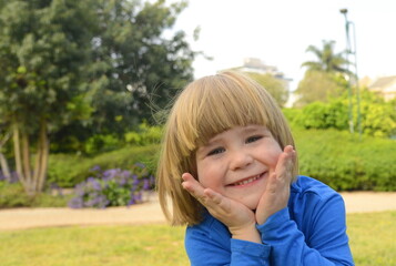 Portrait of a little boy. The child smiles, face close-up. Boy with blond long hair
