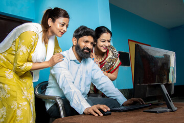 Traditional indian Man with his wife and daughter using computer. Learn skills, Technology in rural...