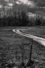 Muddy Dirt Track with Puddles in a Winter Landscape with Bare Trees and Dramatic Sky near Amstetten in the Mostviertel Region of Lower Austria