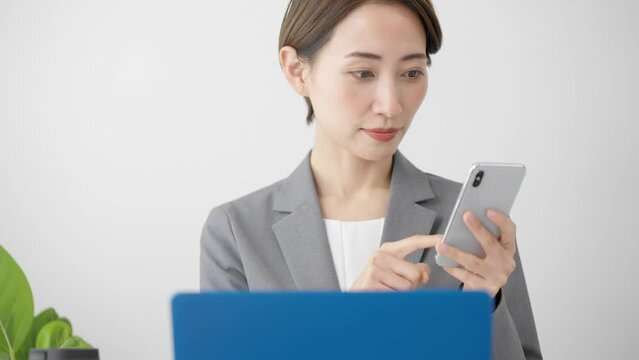 ノートパソコンとスマートフォンを使う若い女性　ビジネスイメージ	