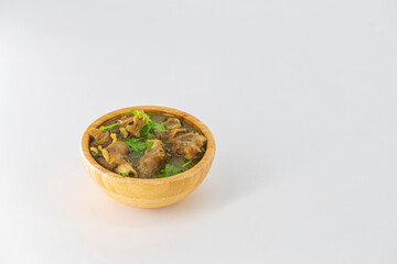 Fresh spicy lamb paya soup in a wooden bowl and ready to eat. Home made mutton soup called paya or attukaal soup in south india. Mutton soup in wooden bowl.