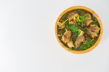 Fresh spicy lamb paya soup in a wooden bowl and ready to eat. Home made mutton soup called paya or attukaal soup in south india. Mutton soup in wooden bowl..