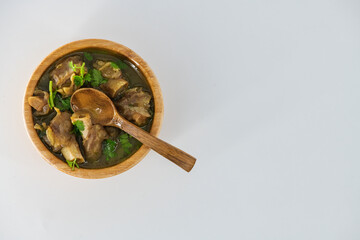 Fresh spicy lamb paya soup in a wooden bowl and ready to eat. Home made mutton soup called paya or attukaal soup in south india. Mutton soup in wooden bowl..